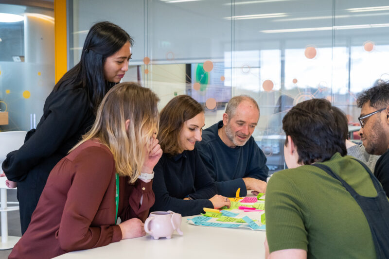 smiling group of people look at table filled with post-its